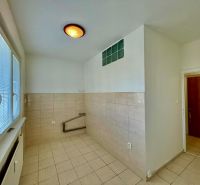 An empty kitchen area with light tiles in a studio apartment.