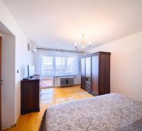 Bedroom in a family house with wood-patterned flooring, wardrobes, and a television.