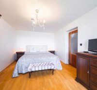 A bedroom in a family house with a bed, wardrobe, dresser, and floor with a wooden decor.