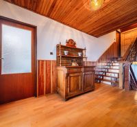 Family house with wood-decor flooring and wooden wall paneling, rustic furniture.