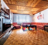 Living room in a family house with a wooden decor floor and an extensive sofa.