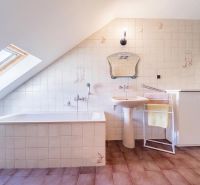 An attic bathroom in a family house with a bathtub, a sink, and a skylight.