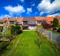 A family house in Rimavská Sobota with a garden, lawn, and flowers, blue sky.