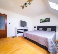 A bedroom with a bed and a wooden decor floor in a family house.