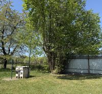 A residential plot in Trenčín on Biskupická Street with trees and a lawn.