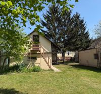 A garden with a house and large trees on Biskupická in Trenčín, suitable for residential land.