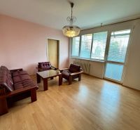 Living room in a three-room apartment with a wooden decor floor and a leather sofa set.