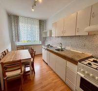 A kitchen in a 3-room apartment with a dining table and a floor with a wood decor.