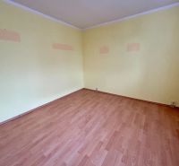 A room with a wooden decor floor in a 3-room apartment. The walls are light yellow.