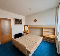 A bedroom in a 3-room apartment with a blue carpet and wooden furniture.