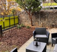 Garden seating at a 2-room apartment on Veterná Street in Trnava with deciduous trees.