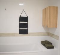 Bathroom of a 2-room apartment with a bathtub and white tiles, complemented by wooden cabinets.