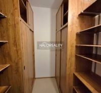 A wardrobe in a 3-room apartment with a wooden decor of cabinets and shelving system.