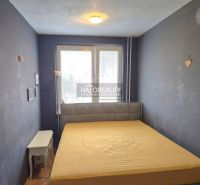 A bedroom in a 3-room apartment with black walls, a large window, and simple furniture.