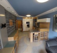 A kitchen in a 2-room apartment with light furniture and a blue ceiling.