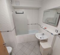 A bathroom with a bathtub, sink, and toilet in a 2-room apartment.