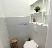 A bathroom with a wooden decor floor and white tiles in a 3-room apartment.