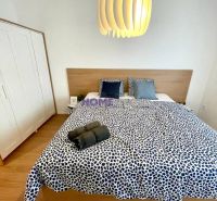 Bedroom in a 3-room apartment with a wood-patterned floor, patterned bed linen, and a modern light fixture.