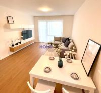 Living room with kitchen in a 3-room apartment with a wooden decor floor and white furniture.
