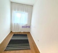 A narrow room with a wooden decor floor and a striped carpet in a 3-room apartment.