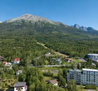 Hotels and guesthouses in the High Tatras surrounded by forest with mountains in the background.