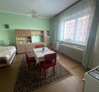 Green wall with furniture, dining table, bed in a family house with wood-patterned flooring.