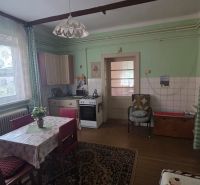 A kitchen in a family house with a dining table, floral curtains, and a stove.