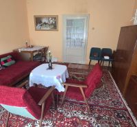 Living room in a family house with a carpet, wooden furniture, and paintings on the walls.