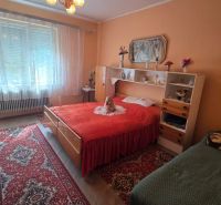 A bedroom in a family house with an oriental rug and a bed with a red blanket.