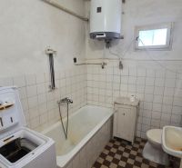 A bathroom in a family house with a bathtub, washing machine, and gas boiler.