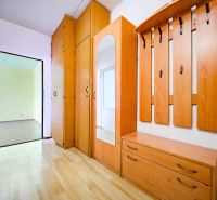 The entrance hall of a 2-room apartment with a wooden decor floor and built-in wardrobes.