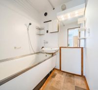 Bathroom with a bathtub and shower in a 2-room apartment, floor with wooden decor.