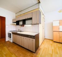 A kitchen in a 2-room apartment with a wood-patterned floor and a simple kitchen unit.
