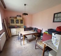 A room in a family house with wooden furniture and simple chairs.