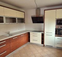A kitchen with a corner unit in a family house, white cabinets, and ceramic flooring.