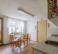 A kitchen in a family house with a dining table and an entrance to the living room.