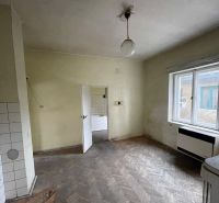 A room with a wooden decor floor and an older radiator in a family house.
