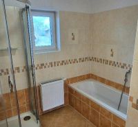 A bathroom with a corner shower and a bathtub in a family house.