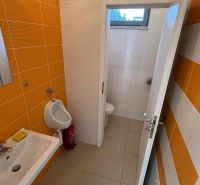 A restroom with orange tiles and ceramic accessories in commercial premises.