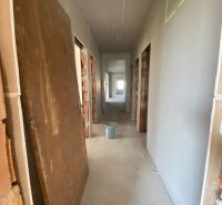 A hallway in a family house with construction material and a bucket on the floor.