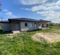 A family house in Encs with a porch on a spacious lawn under a clear sky.