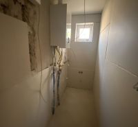 A narrow technical room in a family house with wiring and a small window.