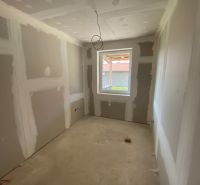 A room under construction in a family house with unfinished wall surfaces and a concrete floor.