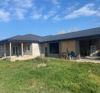 A family house in Encs, unplastered with a dark roof and green lawn.