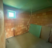 A construction room in a family house with brick walls and a small window.