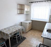 A kitchen in a 3-room apartment with a dining table, chairs, and a kitchen unit.
