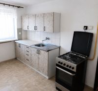 Kitchen in a 3-room apartment with a gas stove and curtains, floor with wood decor.