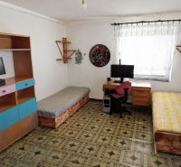 A room in a 3-bedroom apartment with a desk and beds.