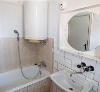 Bathroom with a bathtub, sink, and mirror in a 3-room apartment.