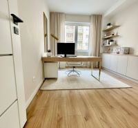 A bright study in a 4-room apartment with a wooden decor floor and a desk.